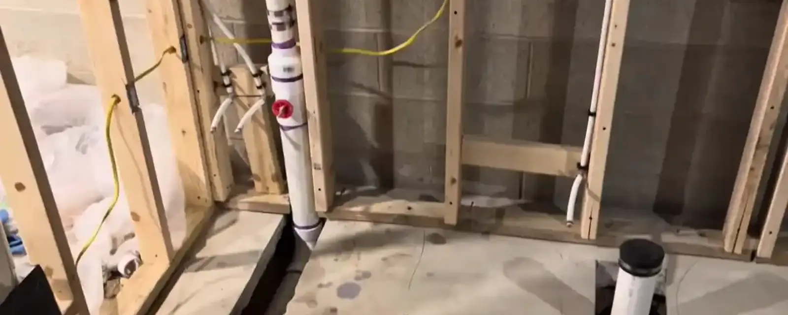 Framed basement wall with a capped drain stub and rough-in plumbing