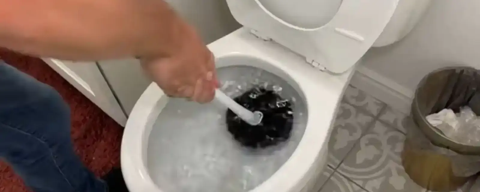 Hand using a brush in a toilet bowl with water near the rim
