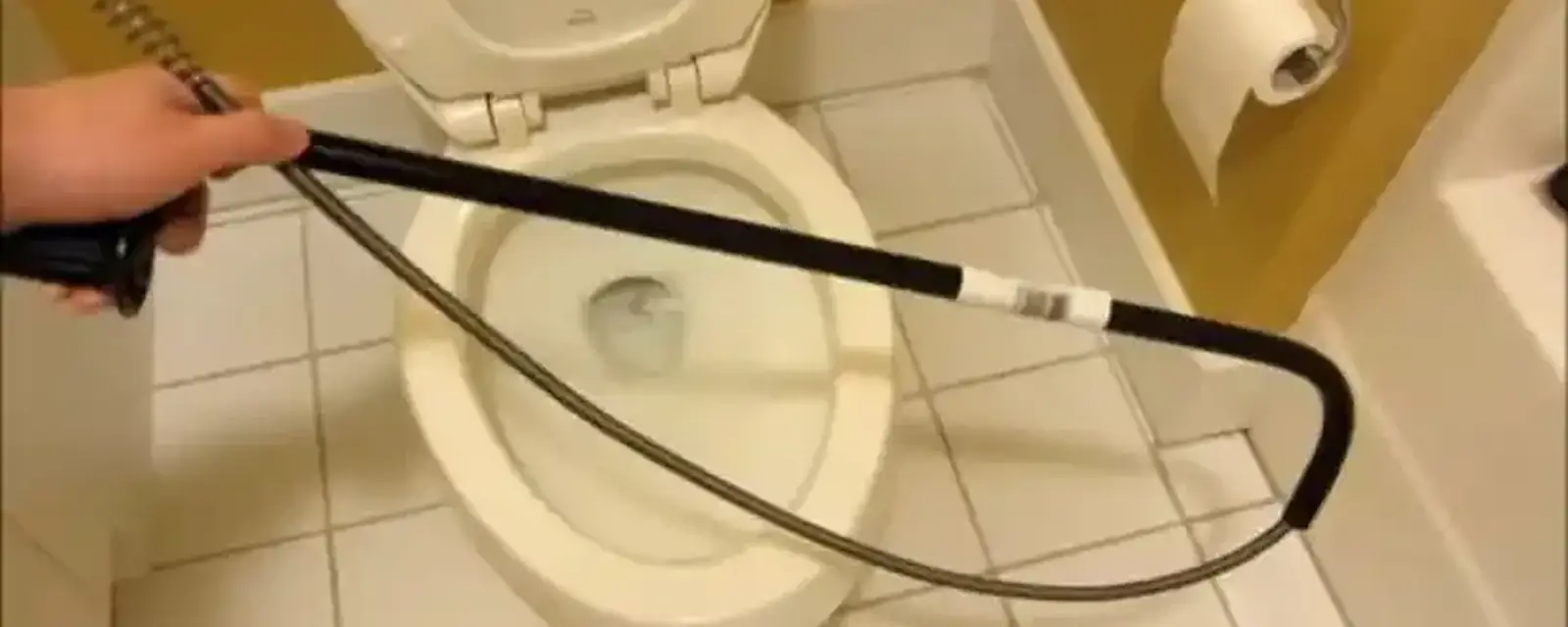 Closet auger cable fed into a toilet bowl to clear a clog