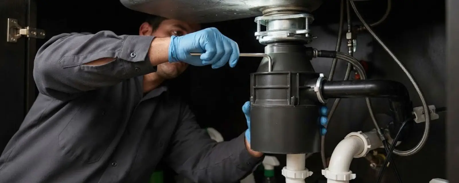 Plumber installing a garbage disposal under a kitchen sink